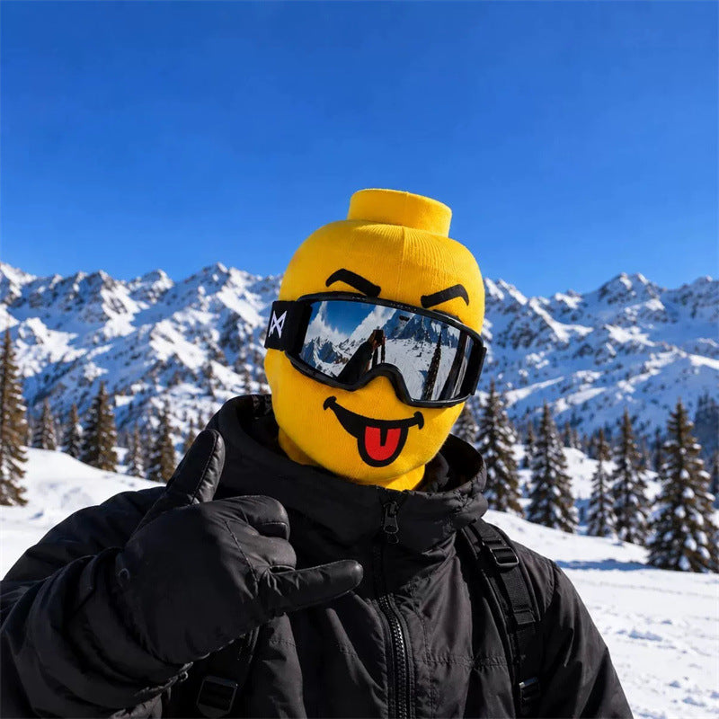 Blockhead ski mask, Tongue Out face, worn with ski goggles on a snowy mountain